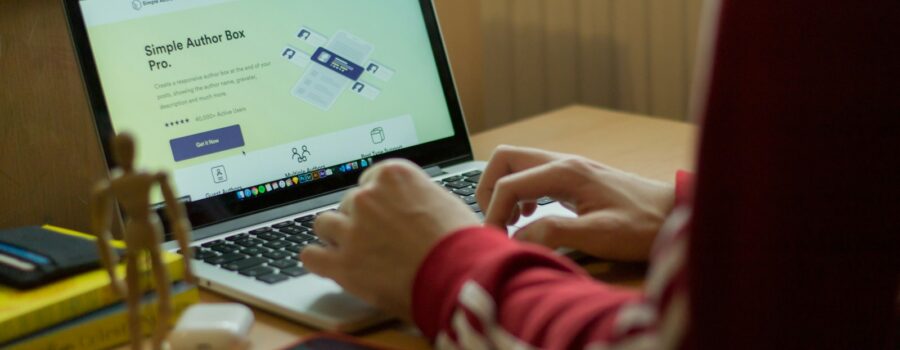 person using macbook pro on brown wooden table
